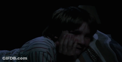 Person In Striped Shirt Laying On Bed In Dark GIF