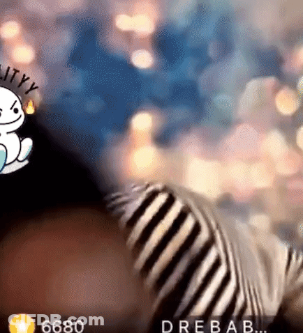 Person In Striped Shirt Sitting In Front Of Christmas Lights GIF