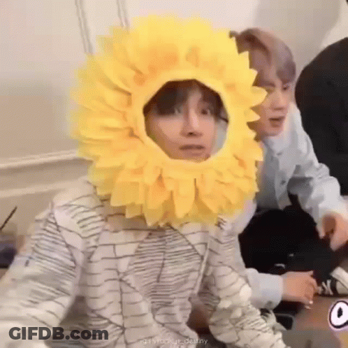 Person In Sunflower Hat Sitting Next To Another GIF