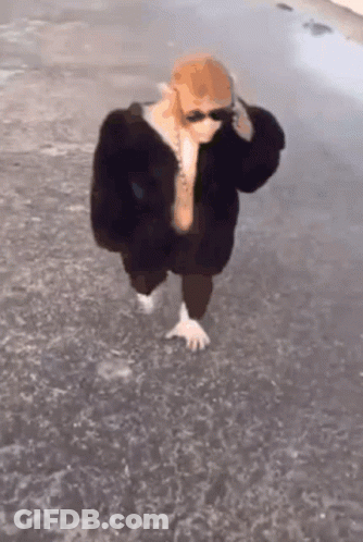 Person In Sunglasses And Fur Coat Walking Barefoot In Water GIF