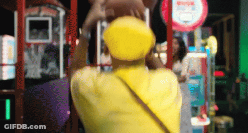 Person In Yellow Hat In Front Of Arcade Sign GIF