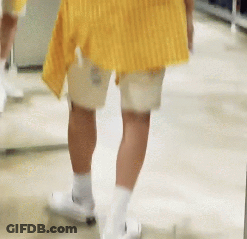 Person In Yellow Shirt And White Shorts Walking Down Hallway GIF