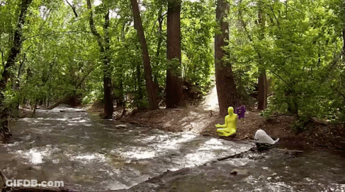 Person In Yellow Suit Sitting On Rock In Stream GIF