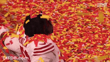 Person Laying In Confetti With Letters LM GIF