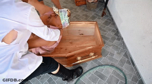Person Laying In Wooden Coffin With Head Bandage GIF