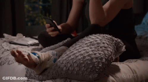 Person Laying On Bed With Bandaged Foot And Cell Phone GIF