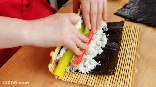 Person Making Sushi Roll With Seaweed And Crab Sticks GIF
