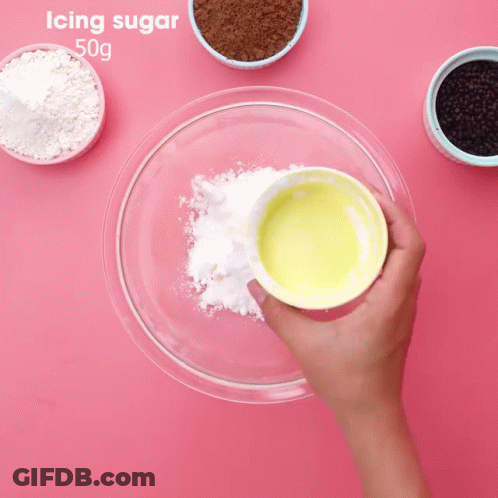 Person Mixing Icing Sugar In Glass Bowl GIF