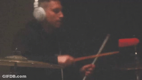 Person Playing Drums In Dark Room With Cross GIF