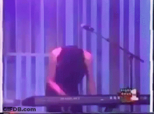 Person Playing Keyboard At Microphone With Purple Light GIF