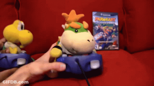 Person Playing Video Game With Stuffed Mario Kart Character GIF