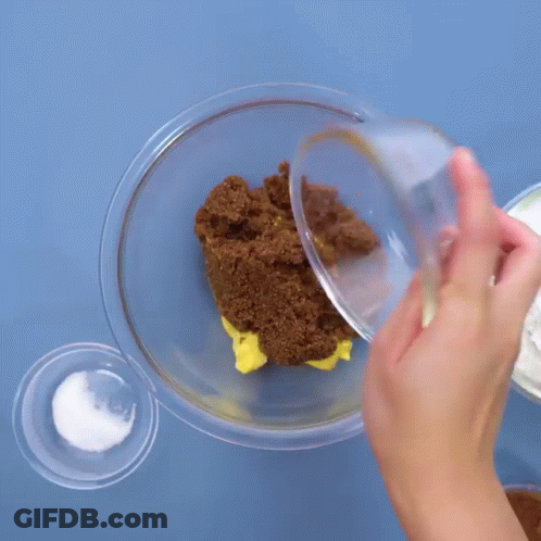 Person Pouring Brown Sugar Into Glass Bowl GIF