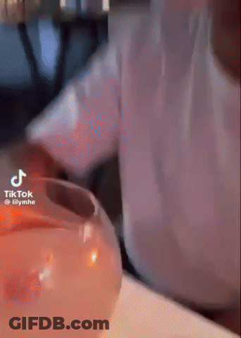 Person Pouring Drink Into Glass With Candle GIF
