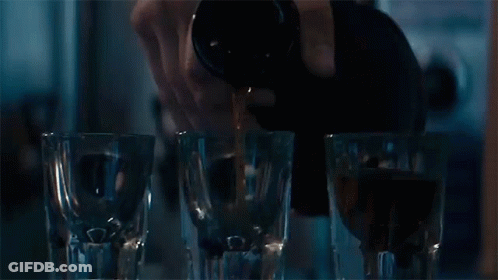 Person Pouring Drink Into Shot Glasses GIF