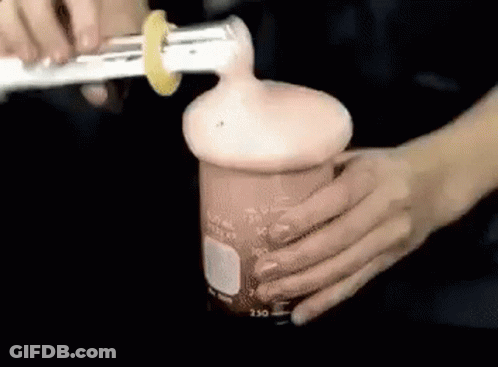 Person Pouring Liquid Into Beaker With Lemon Slice GIF