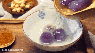Person Pouring Liquid Into Bowl Of Purple Balls GIF