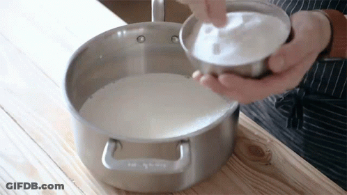 Person Pouring Sugar Into Pot Of Milk GIF