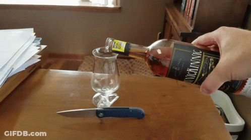 Person Pouring Wine Into Glass With Knife GIF