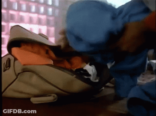 Person Putting Clothes In Bag By Window GIF