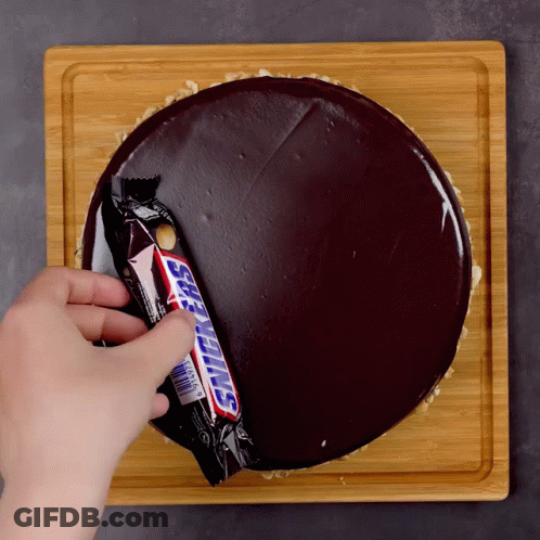 Person Putting Snickers Bar Into Chocolate Cake GIF