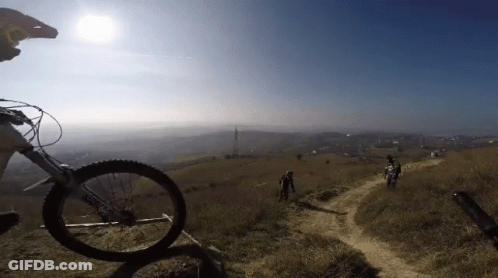 Person Riding Bike On Dirt Path With Giant Tire GIF
