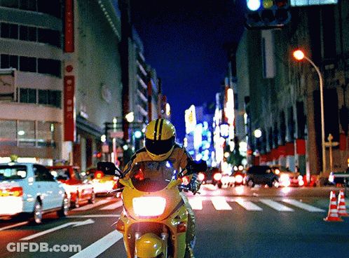 Person Riding Motorcycle Down Street At Night GIF