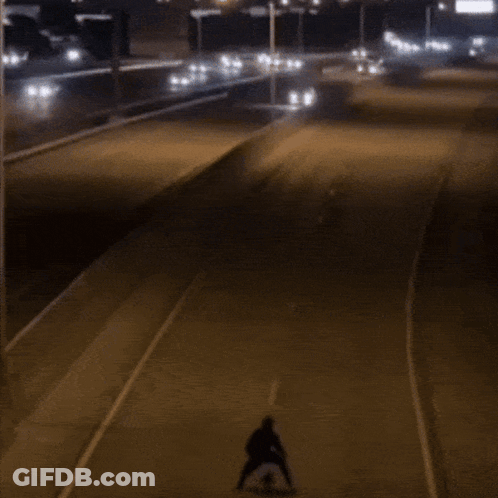 Person Riding Skateboard Down Street At Night GIF
