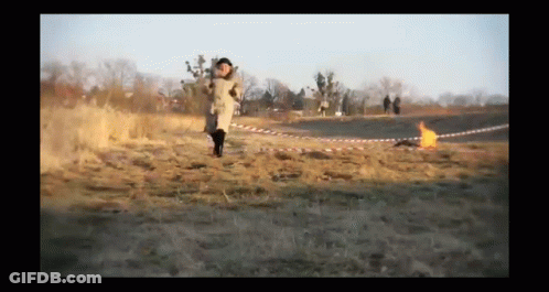 Person Running In Field With Fire Behind GIF