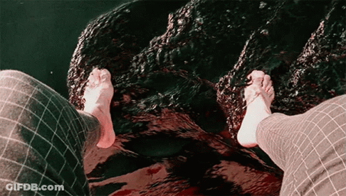 Person's Feet Standing On Rock In Water GIF