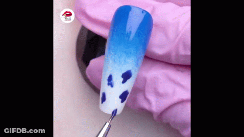 Person's Hand Holding Nail With Blue And White Design GIF