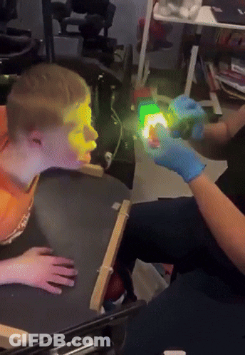 Person Shining Green Light On Boy's Face GIF