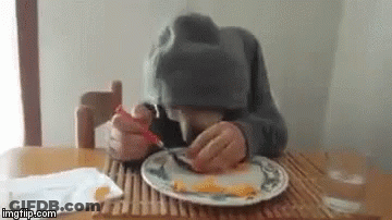 Person Sitting At Table Eating With Fork And Spoon GIF