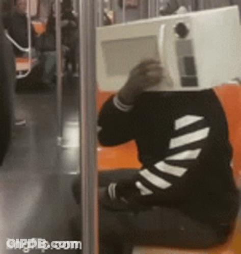 Person Sitting On Bus With Microwave In Front Of Head GIF