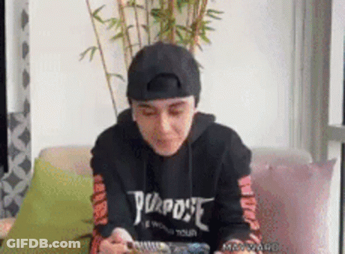 Person Sitting On Couch In Black 'Purpose' Hoodie GIF