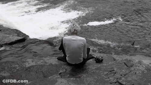 Person Sitting On Rock Near River GIF