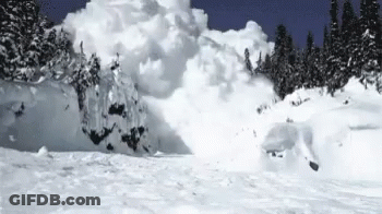 Person Skiing Down Snow-Covered Mountain Slope GIF