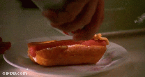 Person Spreading Mustard On Hot Dog GIF