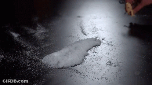 Person Spreading Sugar On Table In Dark Room GIF