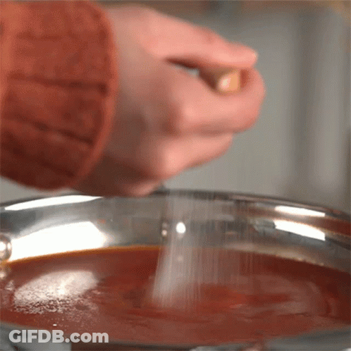 Person Sprinkling Salt Into Pot Of Sauce GIF
