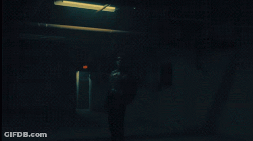 Person Standing In Dark Room With Red Exit Sign GIF