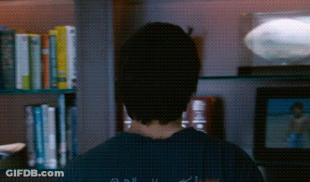 Person Standing In Front Of Bookshelf With Apollo 11 Book GIF
