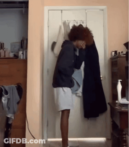Person Standing In Front Of Door With Clothes Hanging GIF