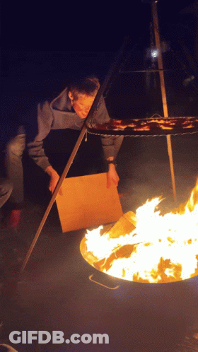 Person Standing In Front Of Fire With Cardboard Box GIF