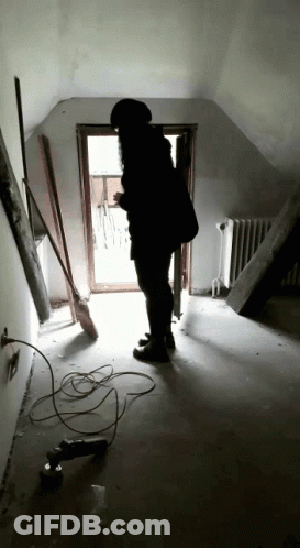 Person Standing In Hallway With Broom And Drill GIF