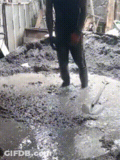 Person Standing In Muddy Puddle Holding Shovel GIF