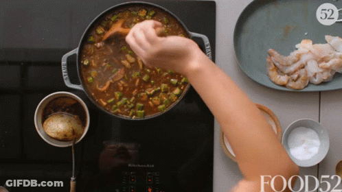 Person Stirring Pot With Wooden Spoon In Front Of Shrimp GIF