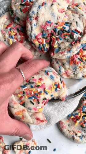 Person Taking Bite Of Cookie With Sprinkles GIF