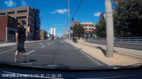Person Walking Down Street At 11:56 GIF
