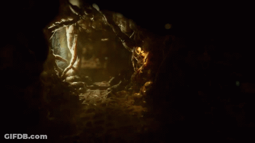 Person Walking In Dark Cave With Green Light On Chest GIF