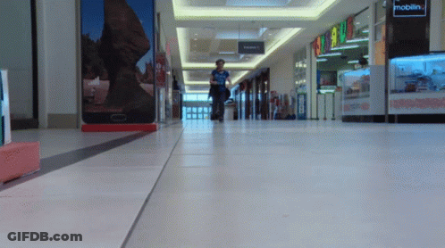 Person Walking In Mall With Mobilin Sign GIF